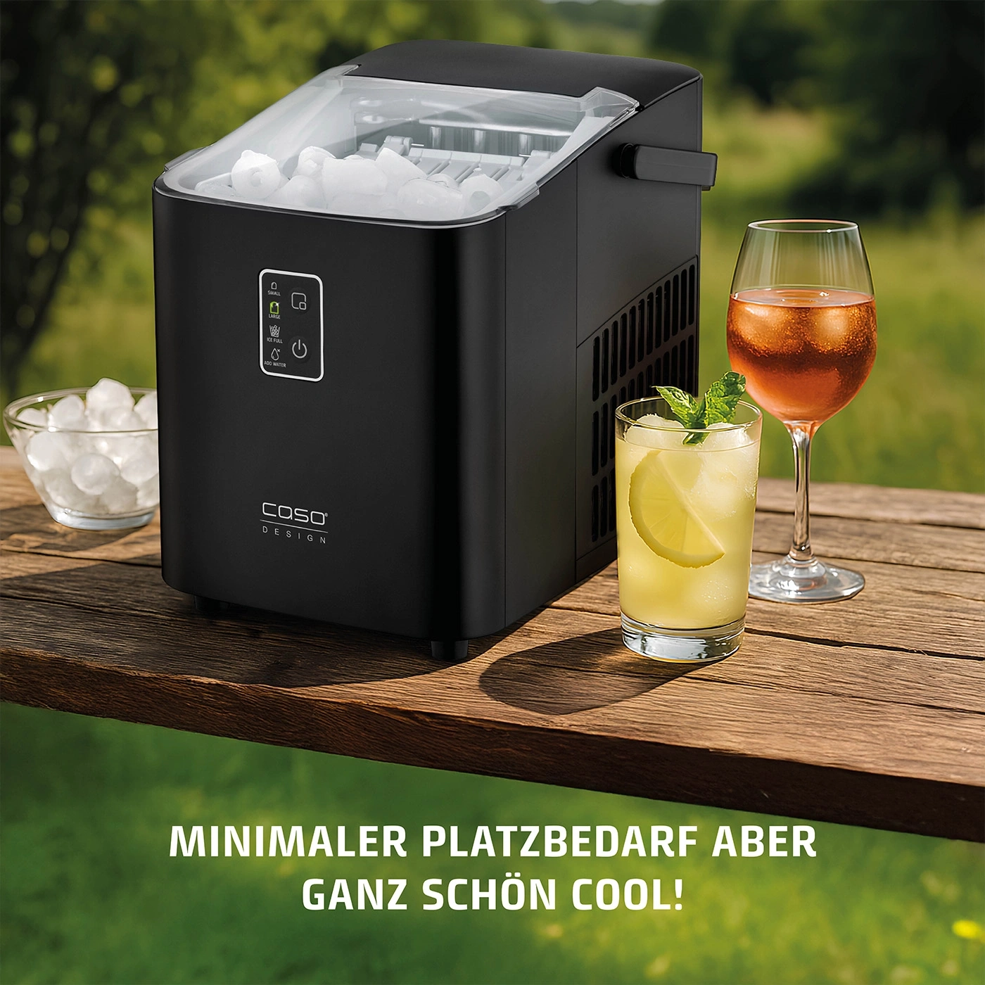 Eiswürfelmaschine mit Getränken auf einem Holztisch im Freien. Minimaler Platzbedarf.