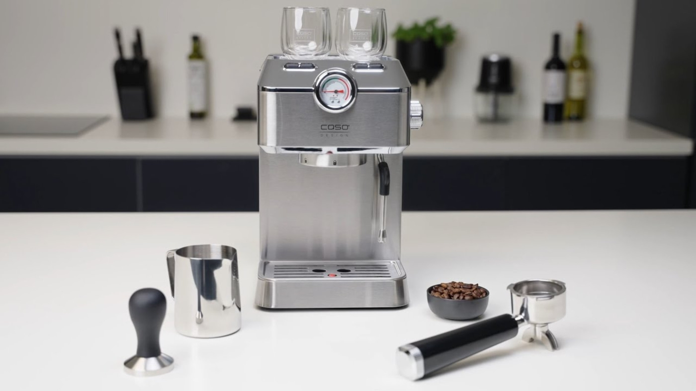 Espresso machine with accessories on a white table in a kitchen setting.