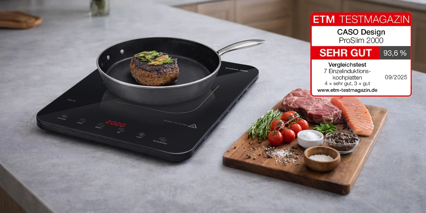 Ein Induktionskochfeld mit einem Steak in der Pfanne und rohem Fleisch und Lachs daneben.