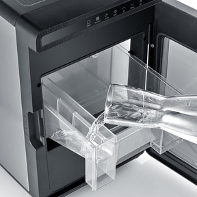 Wasser wird in einen Eisbereiter gegossen, der sich in einem Schrank befindet.