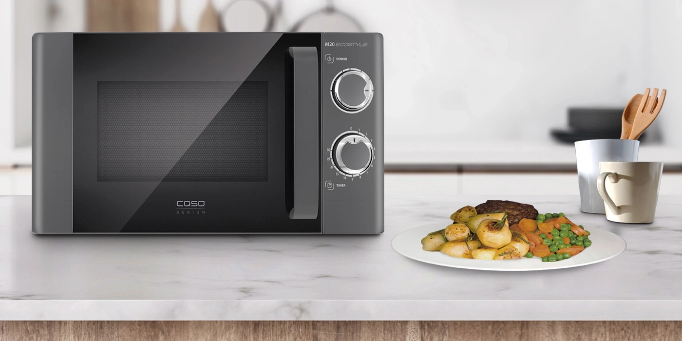 Microwave with food on a table. Plate with vegetables and meat. Kitchen setting.