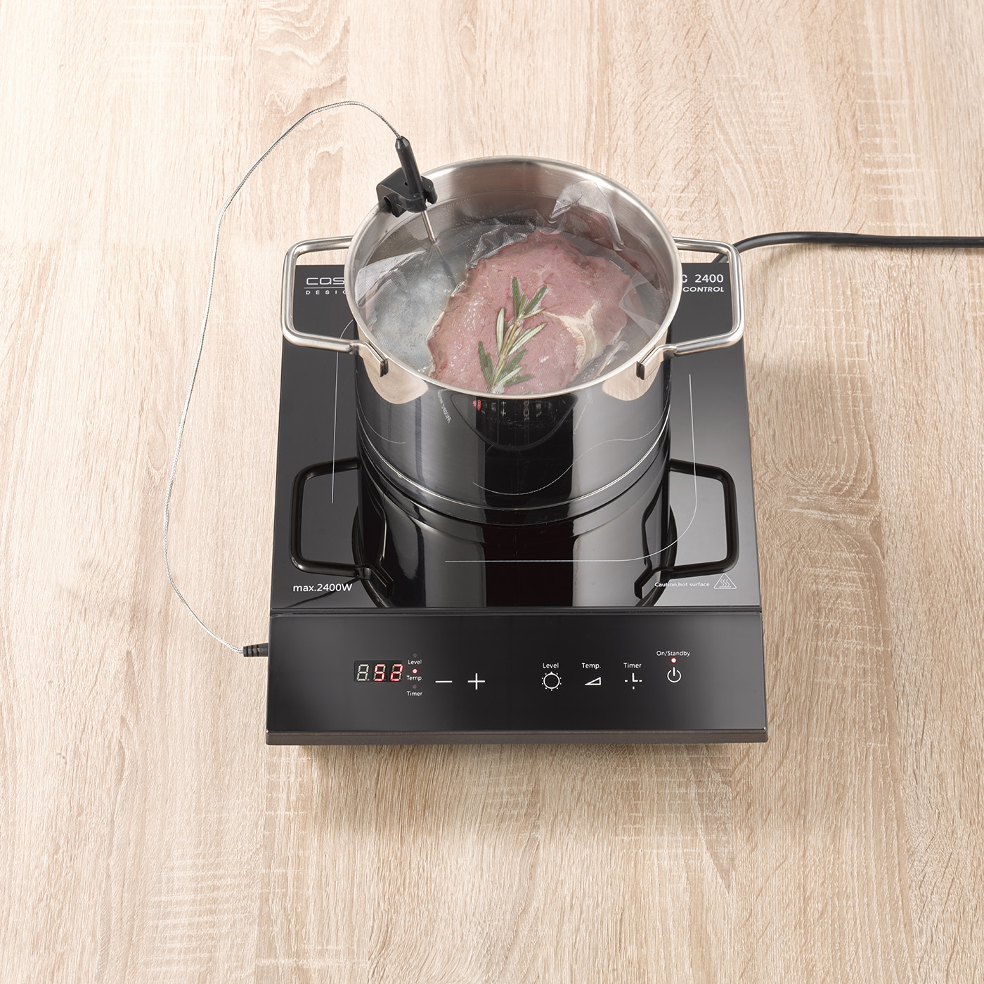 Pot with meat on induction cooktop. Temperature display, herbs, water bath, cooking, kitchen, food, preparation.