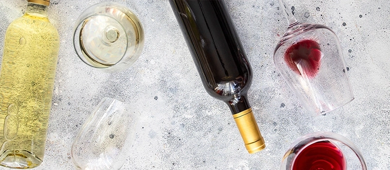 Weinflaschen und Gläser auf grauem Hintergrund, Draufsicht. Rot- und Weißwein.