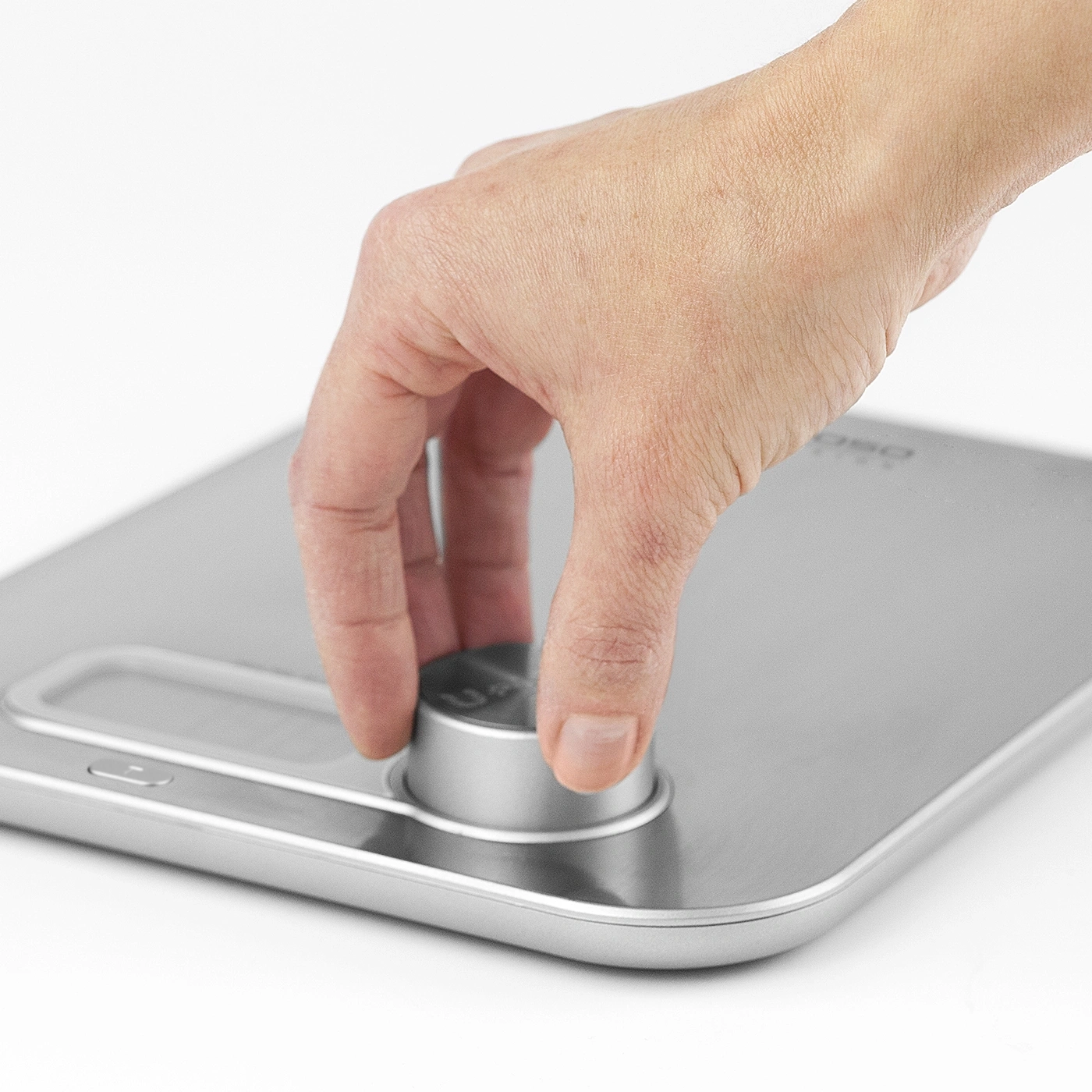 Close-up of a hand turning a knob on a scale, isolated on white background