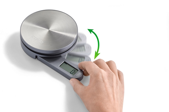 Digital kitchen scale with hand activating the TARE function to zero the weight.