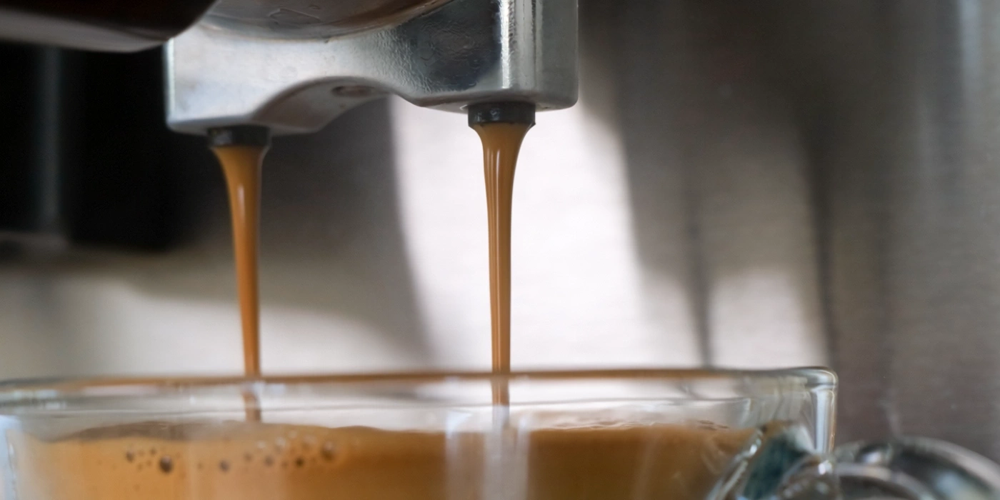 Espressostrahl fließt in eine Tasse aus einer Kaffeemaschine.