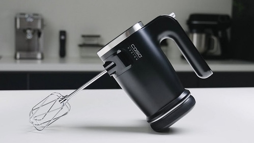 Schwarzer Handmixer auf einer weißen Oberfläche mit Caso Design Logo.