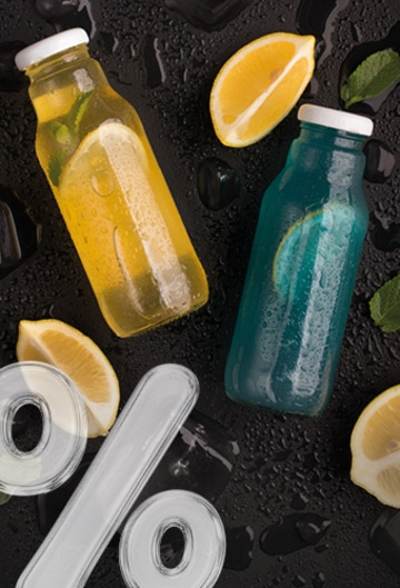 Two bottles of delicious drinks with lemon slices, garnished with ice and mint.