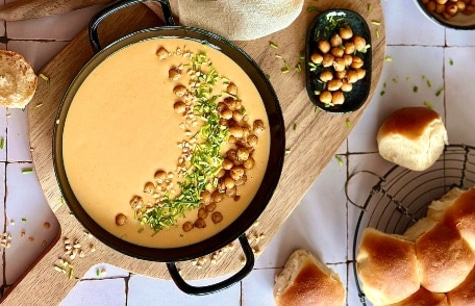 Pumpkin soup with chickpeas and bread, served on a wooden board