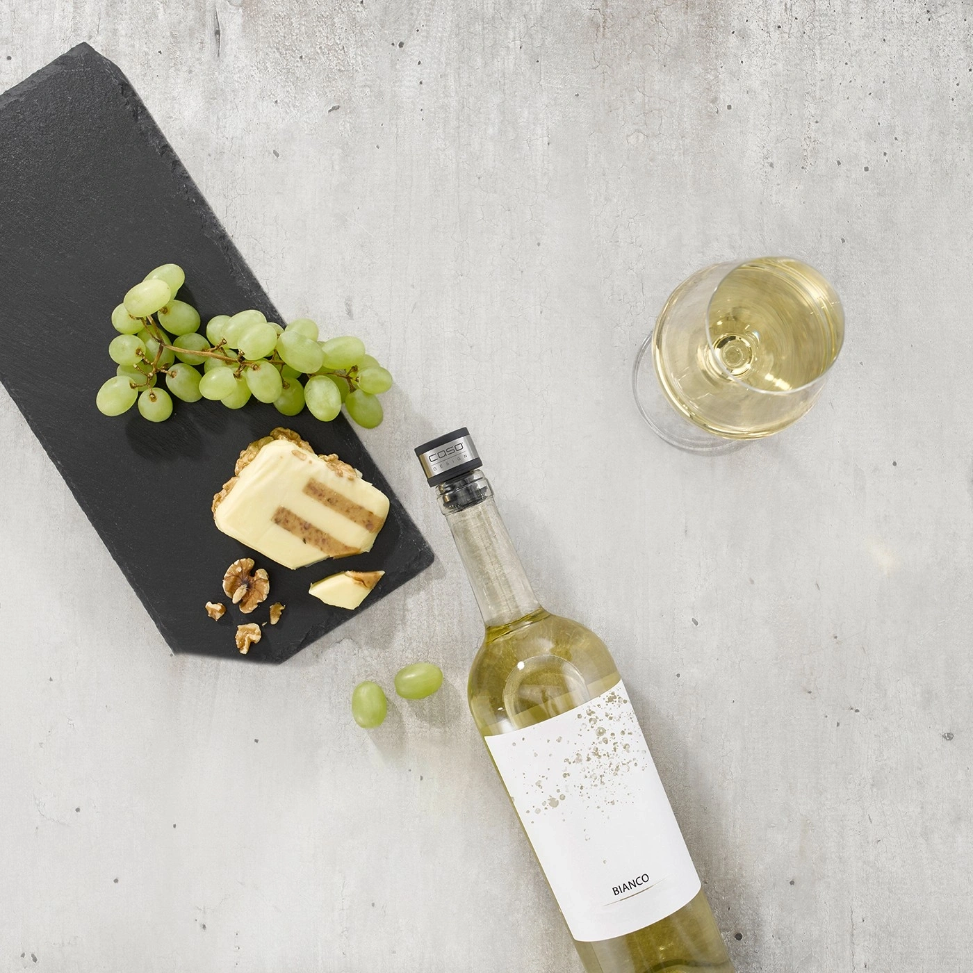 White wine, grapes, cheese, and nuts on a gray background