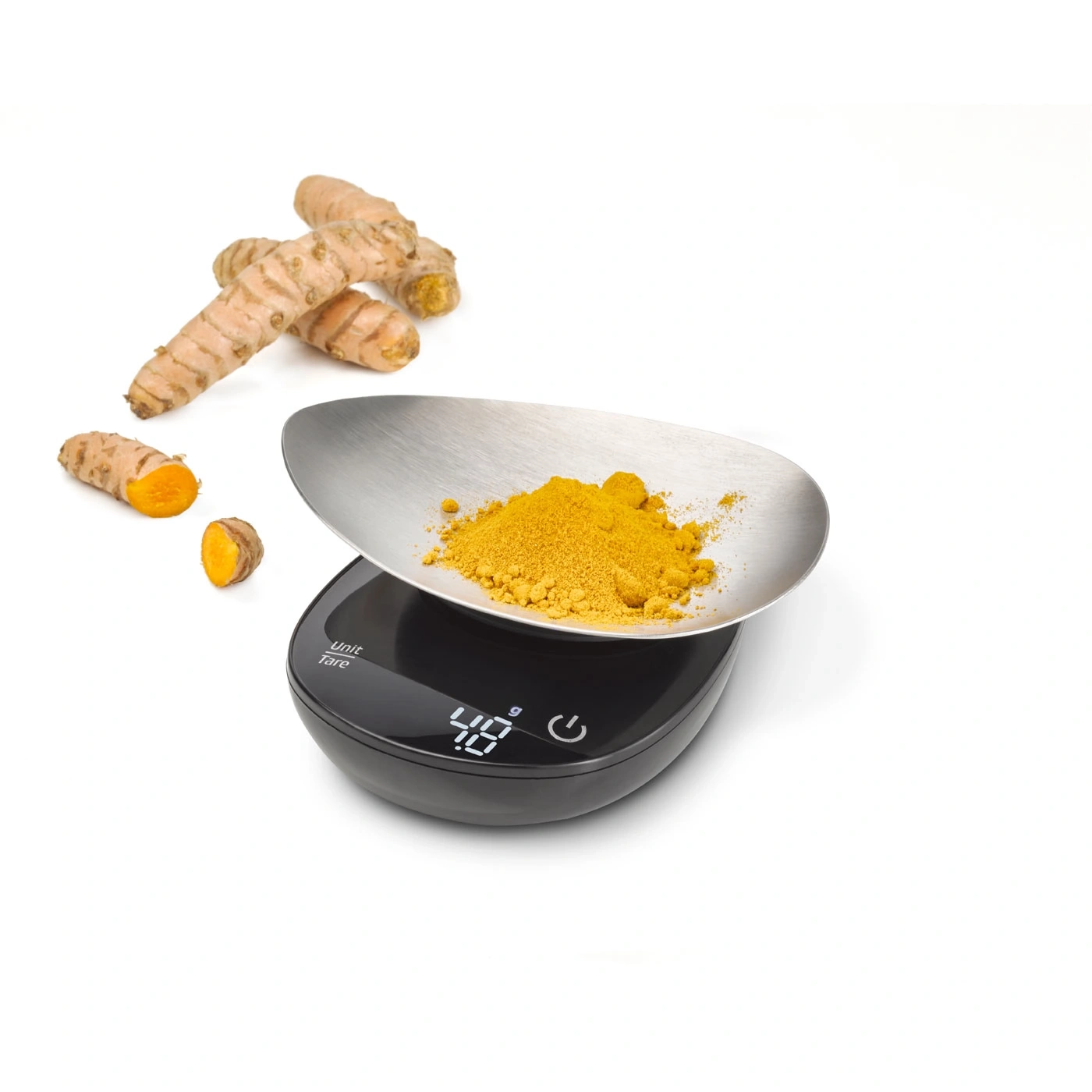 Yellow powder on a scale with turmeric roots in the background