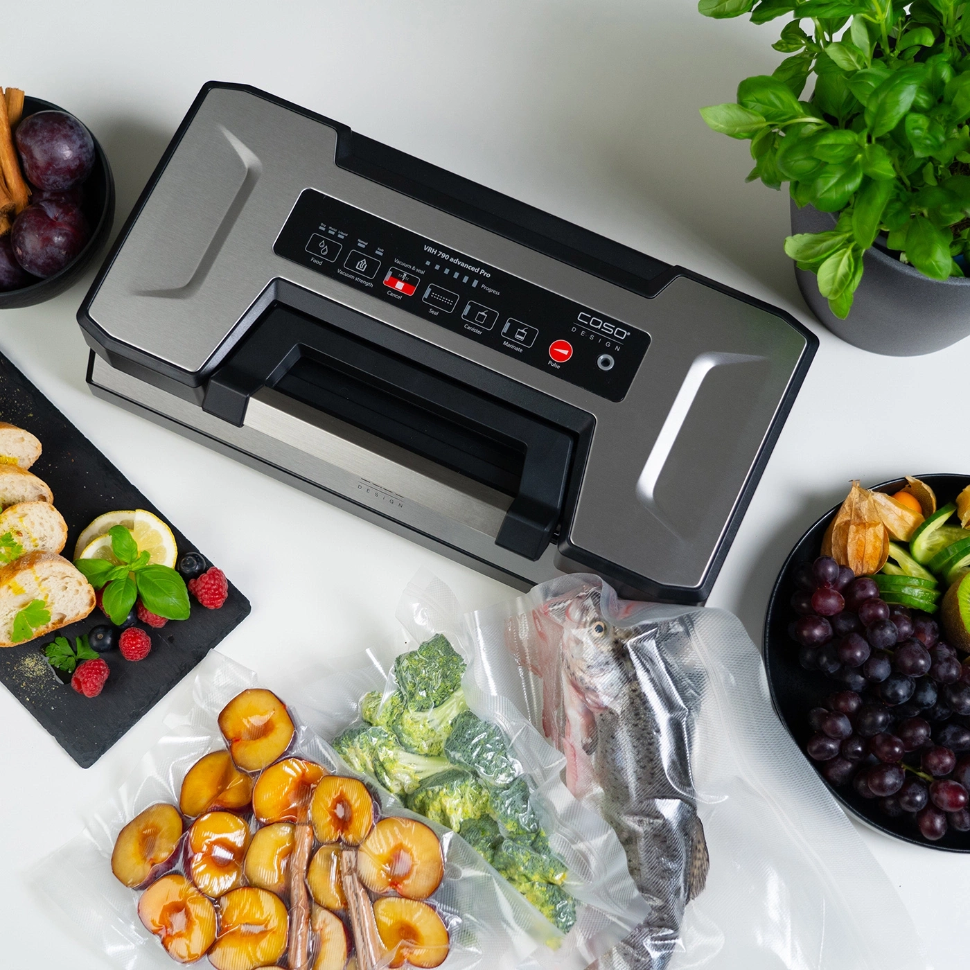 Vacuum sealer with fruits, vegetables, fish, herbs, and fruits on a table.