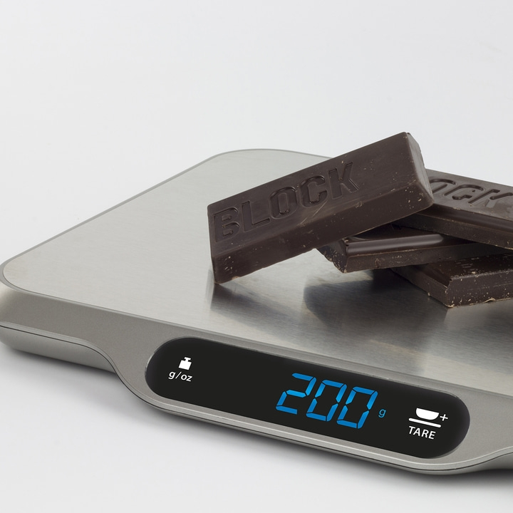 Chocolate pieces on a scale, displaying a weight of 200 grams.