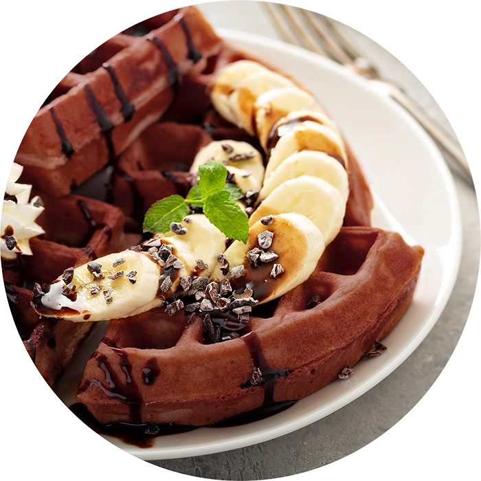 Schokoladenwaffeln mit Bananen, Schokosauce und Minze auf einem Teller