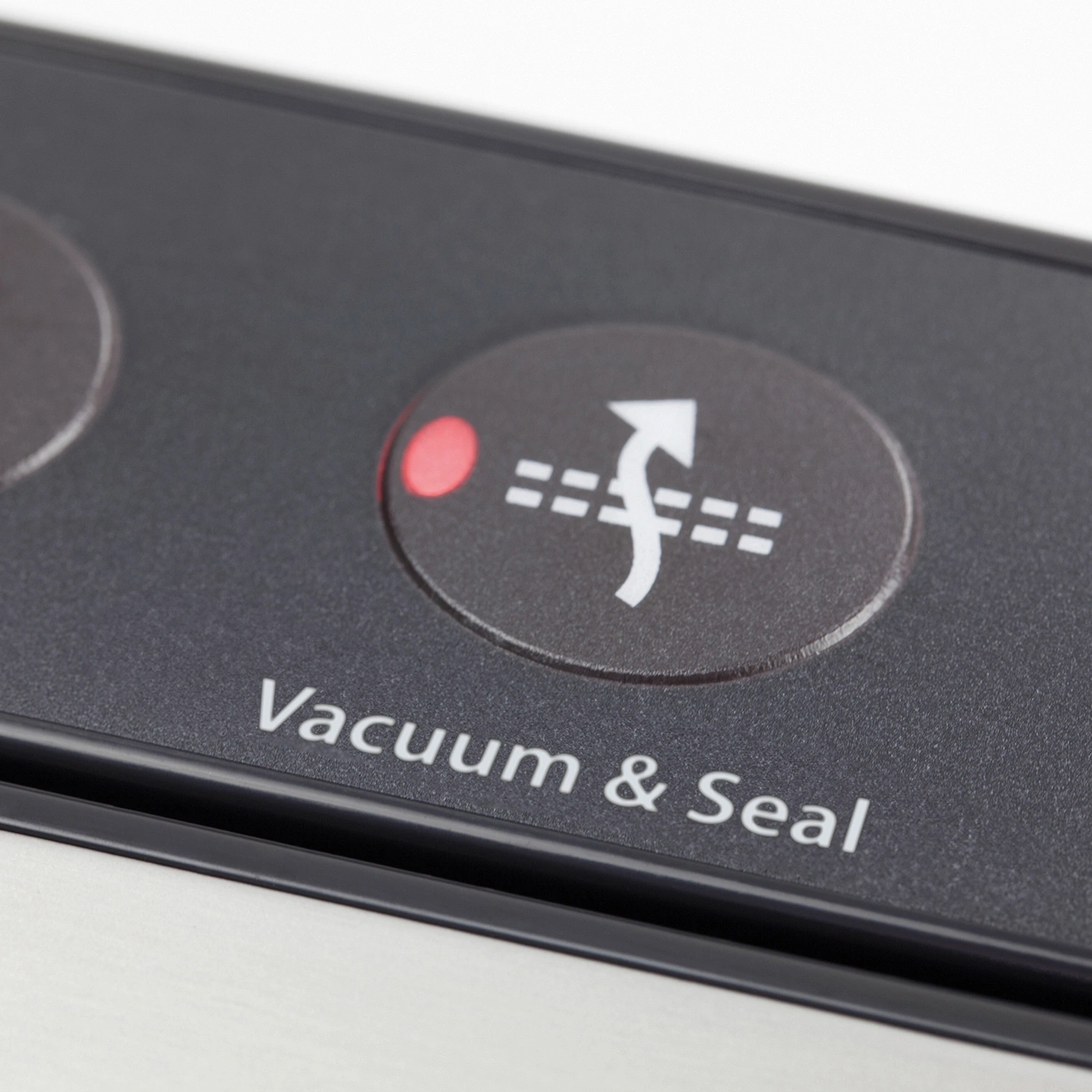 Vacuum and Seal button with red indicator and arrow symbol on black surface.