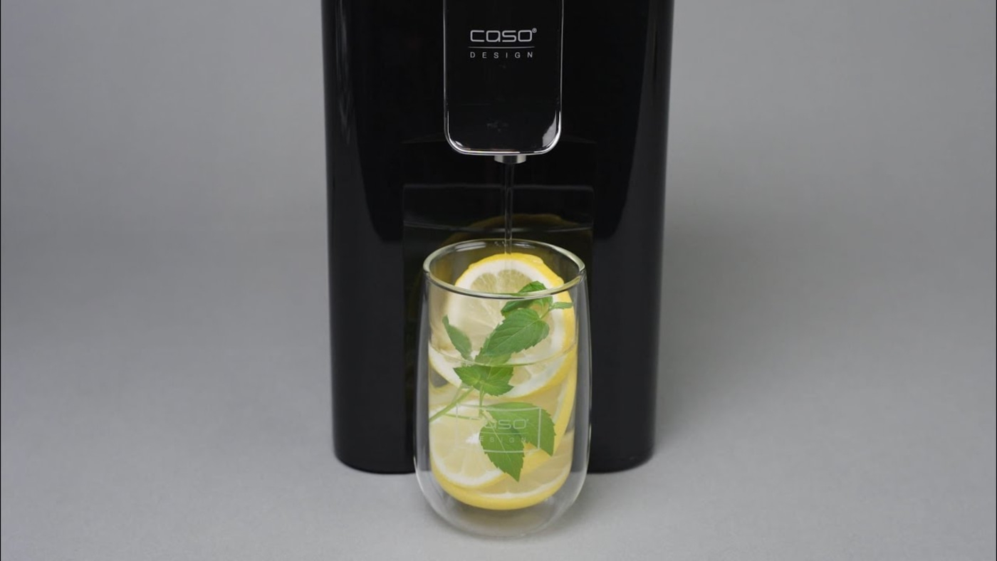 Schwarzer Wasserspender mit Glas, Zitrone und Minze, grauer Hintergrund