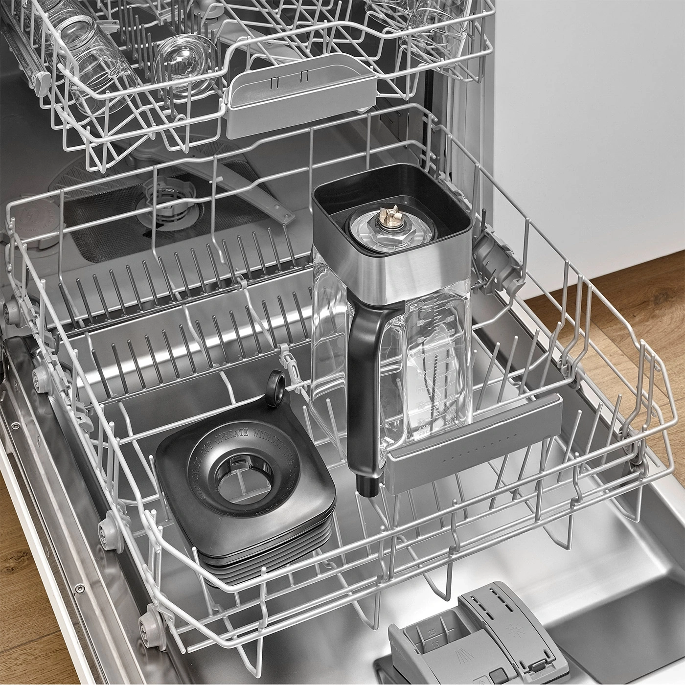 An open dishwasher with dishes and a blender attachment inside.
