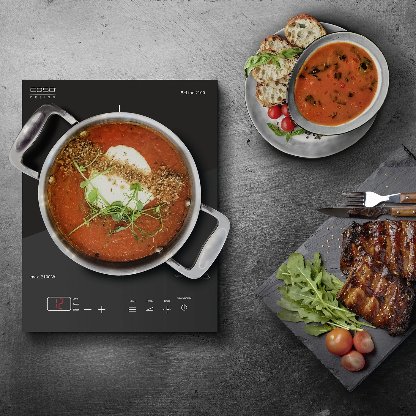 Kochfeld mit Suppe, Brot, Fleisch und Gemüse auf dunklem Hintergrund. Essen zubereiten.