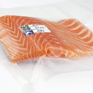 Salmon fillet packaged in foil, with label, date, and weight information.