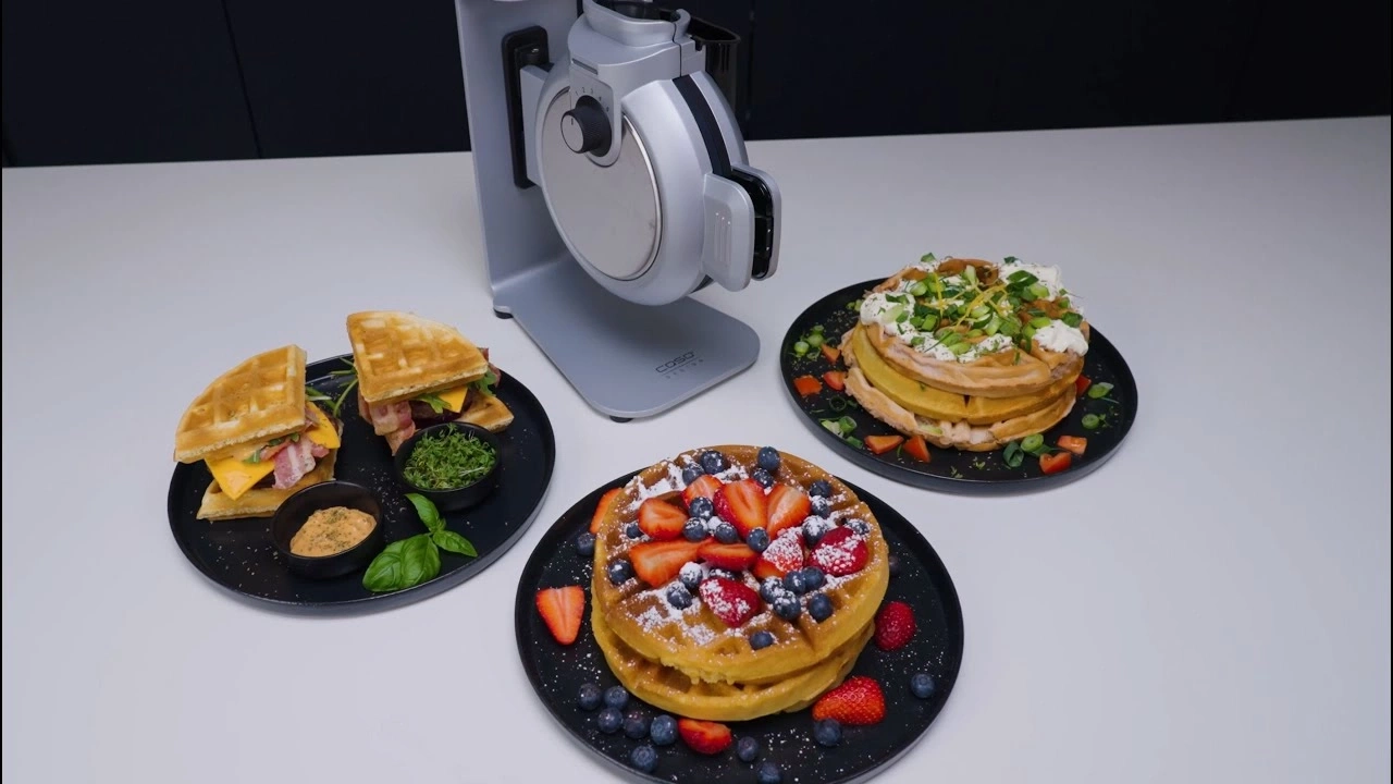 Waffeleisen mit Waffeln, die mit verschiedenen Belägen serviert werden, auf einem Tisch.