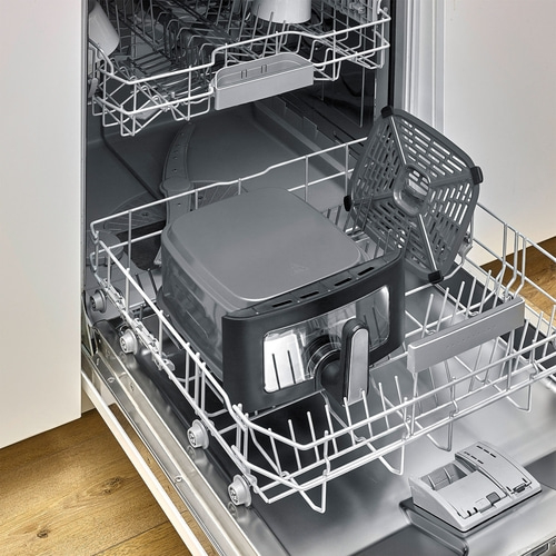 A dishwasher with an air fryer and accessories in the bottom rack.