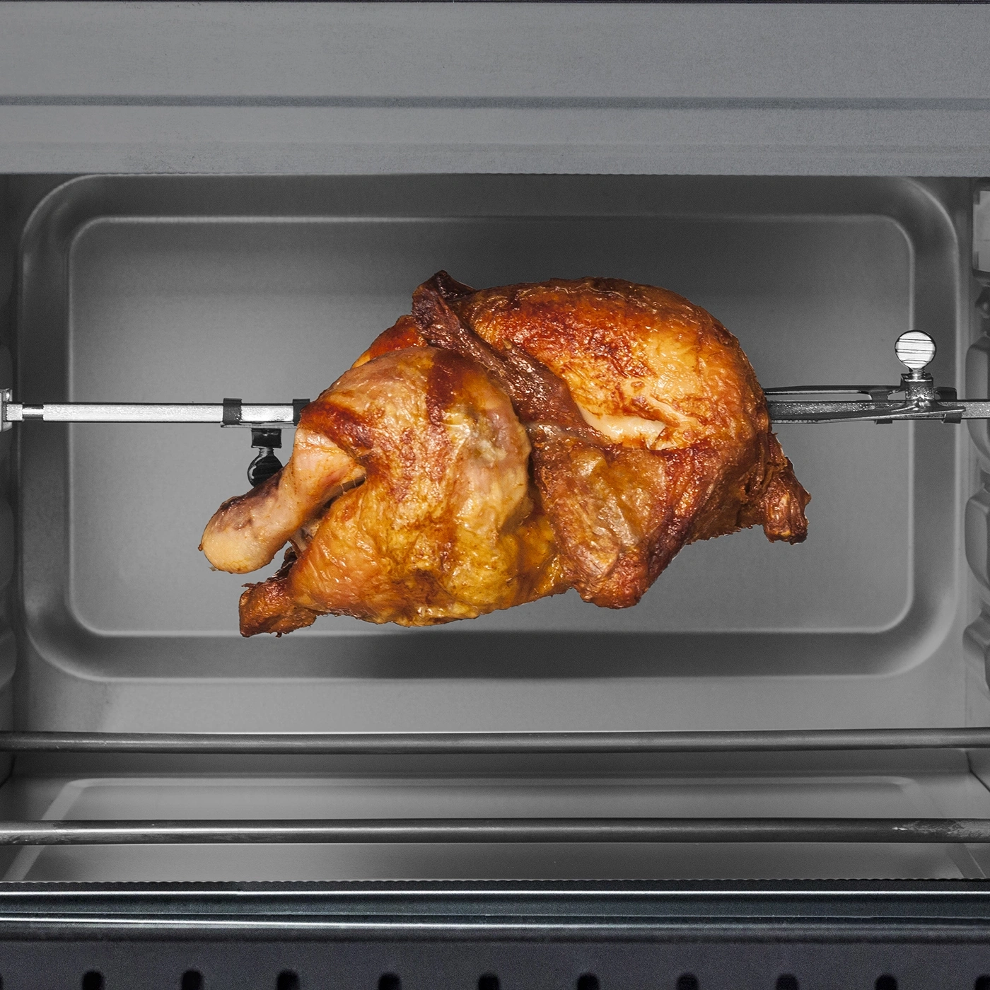 Gebratenes Huhn im Ofen, knusprig und goldbraun, auf dem Spieß