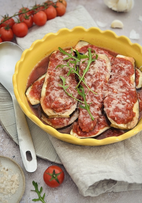 Auberginenauflauf mit Tomaten und Käse in gelber Schüssel, serviert