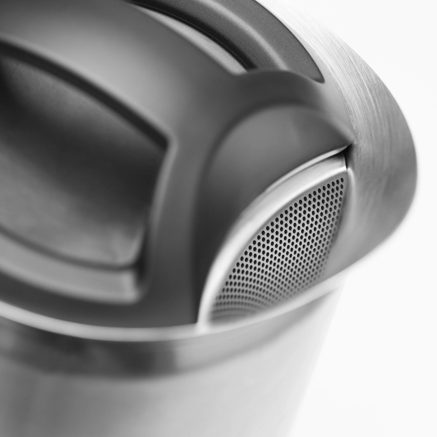 Close-up of a silver metal object with holes and a handle, minimalist design