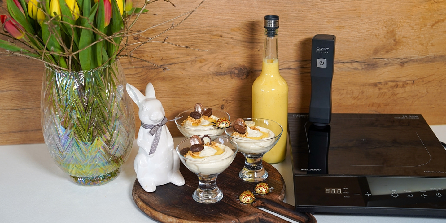 Osterdekoration mit Dessert, Hase, Blumen, Getränk und Kochfeld.