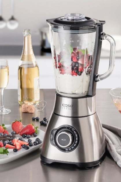 Edelstahl-Mixer mit Früchten, Champagner und Erdbeeren auf einem Tisch