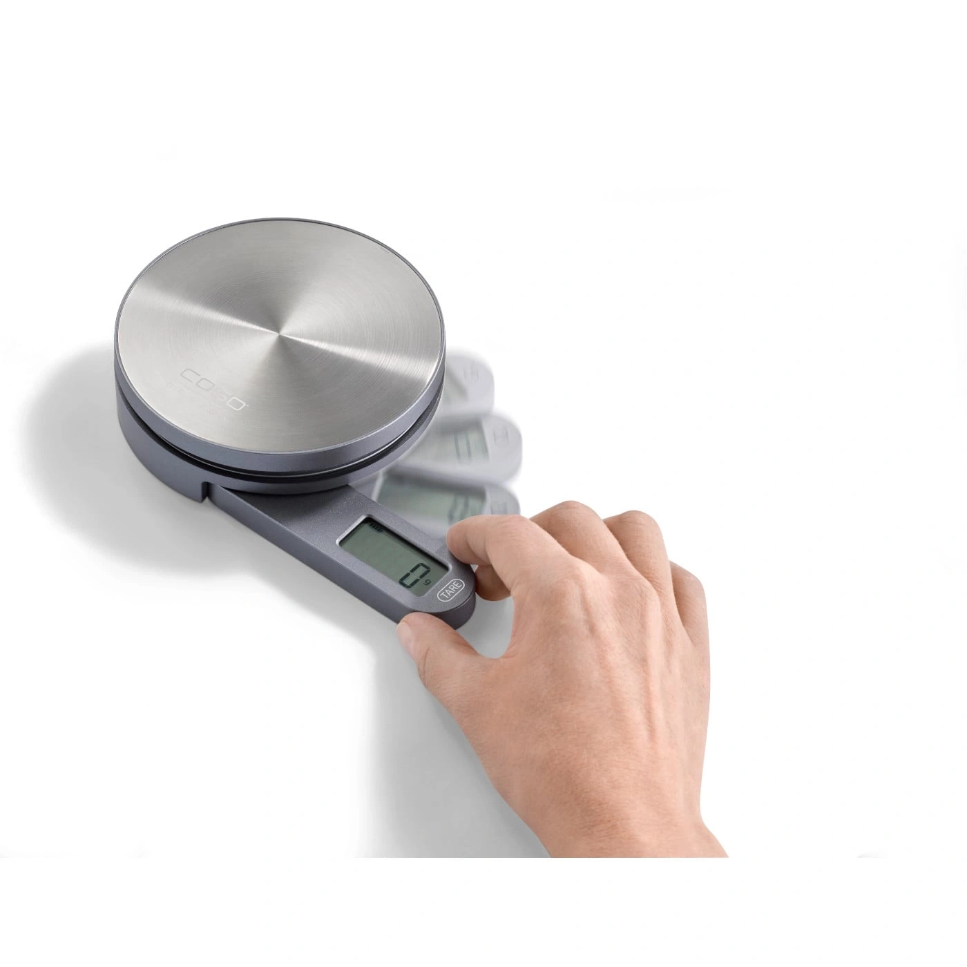 Kitchen scale with hand pressing the button to tare the weight.