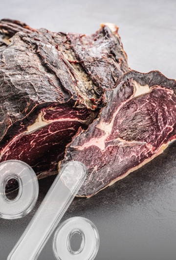 Dried meat with glass percent sign on dark background
