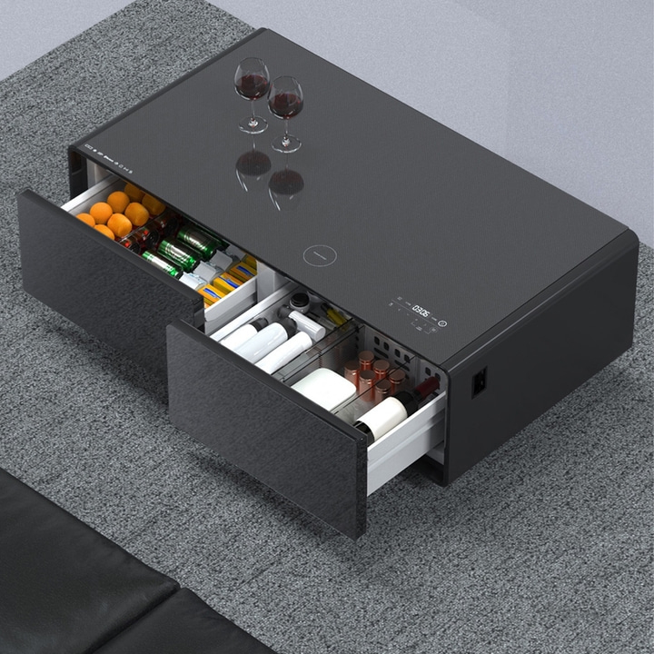 Black coffee table with drawers, drinks, and glasses on the table.