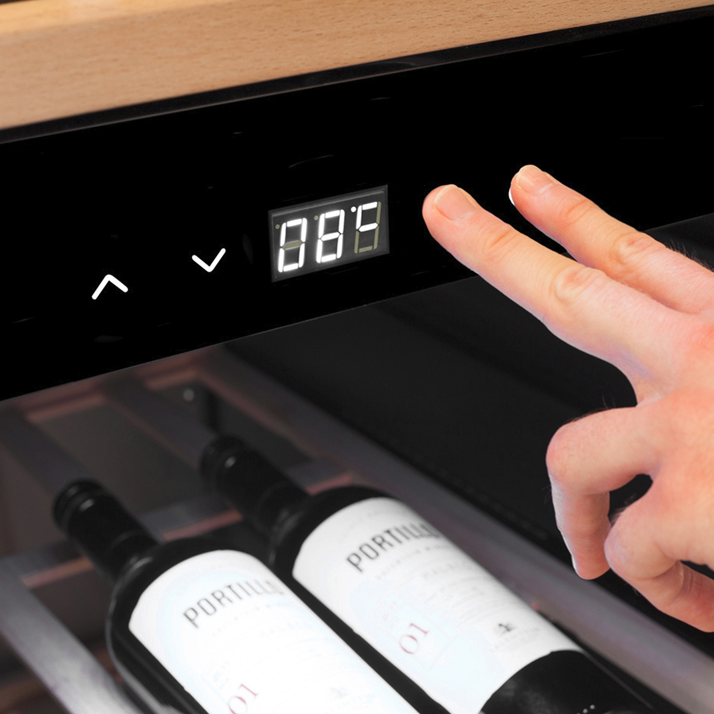 Weinkühler mit Temperaturanzeige und Bedienung durch Finger, Weinflaschen im Hintergrund