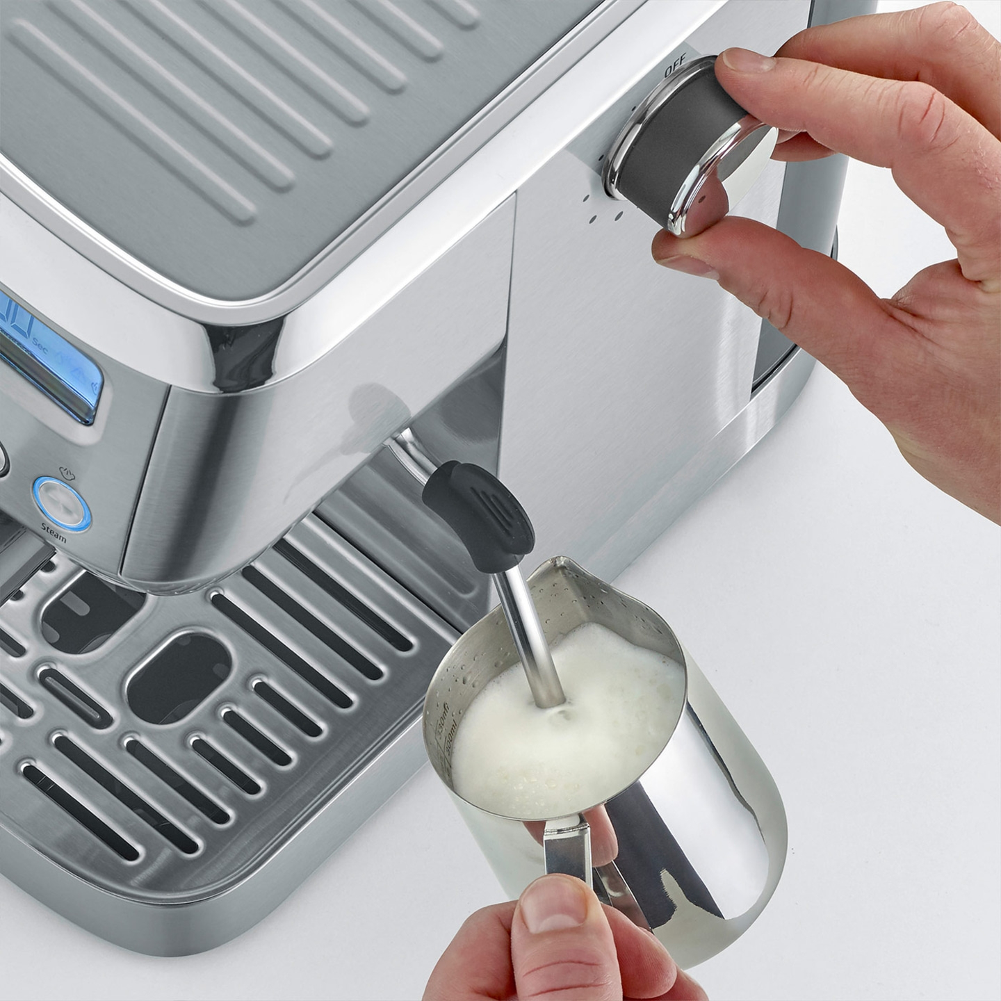 Nahaufnahme einer Person, die Milch mit einer Espressomaschine aufschäumt.