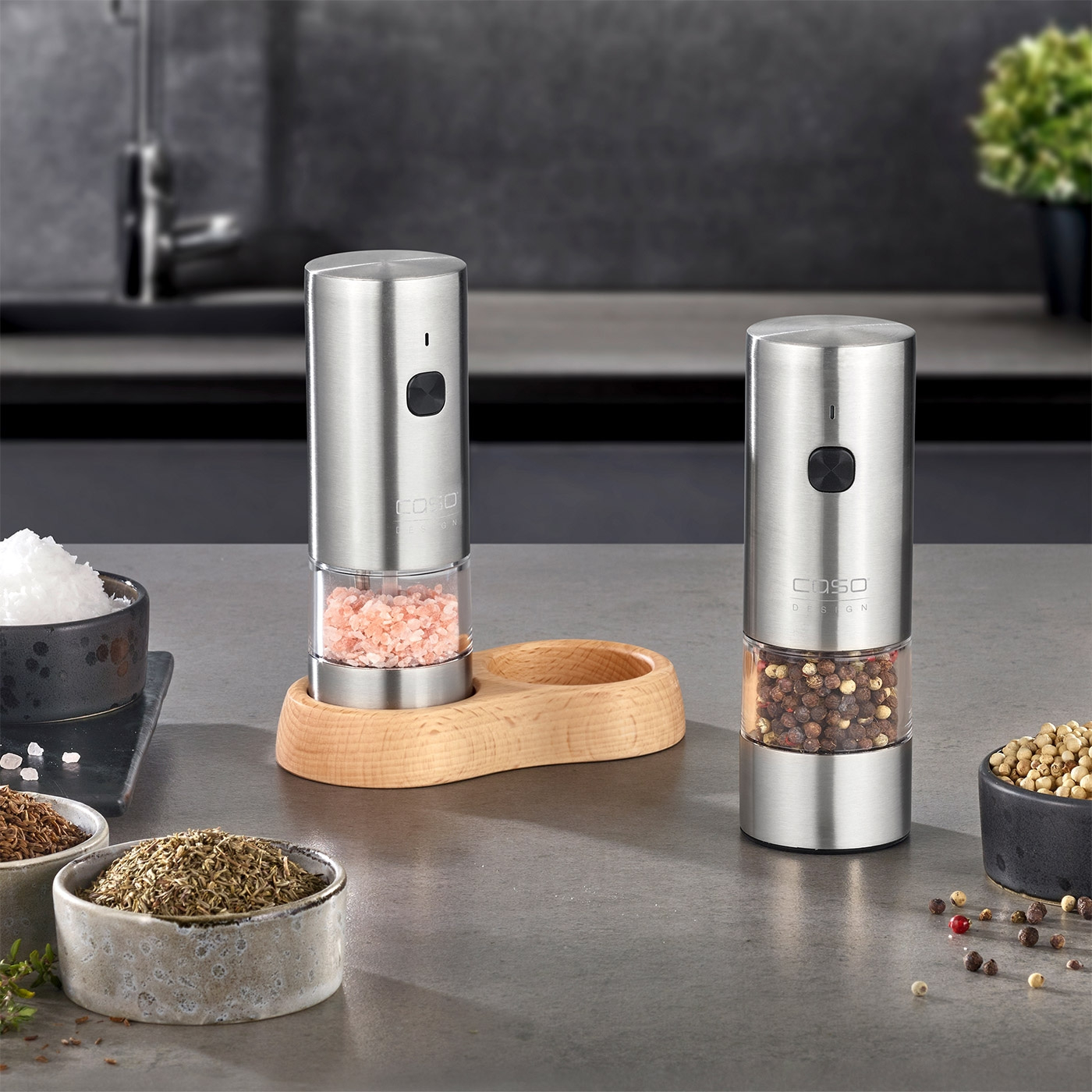 Two electric pepper mills with spices on a kitchen table, close-up shot.
