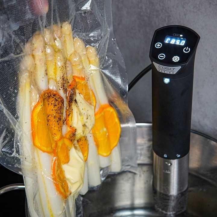 Asparagus with oranges being sous vide, with a thermostat in the water.