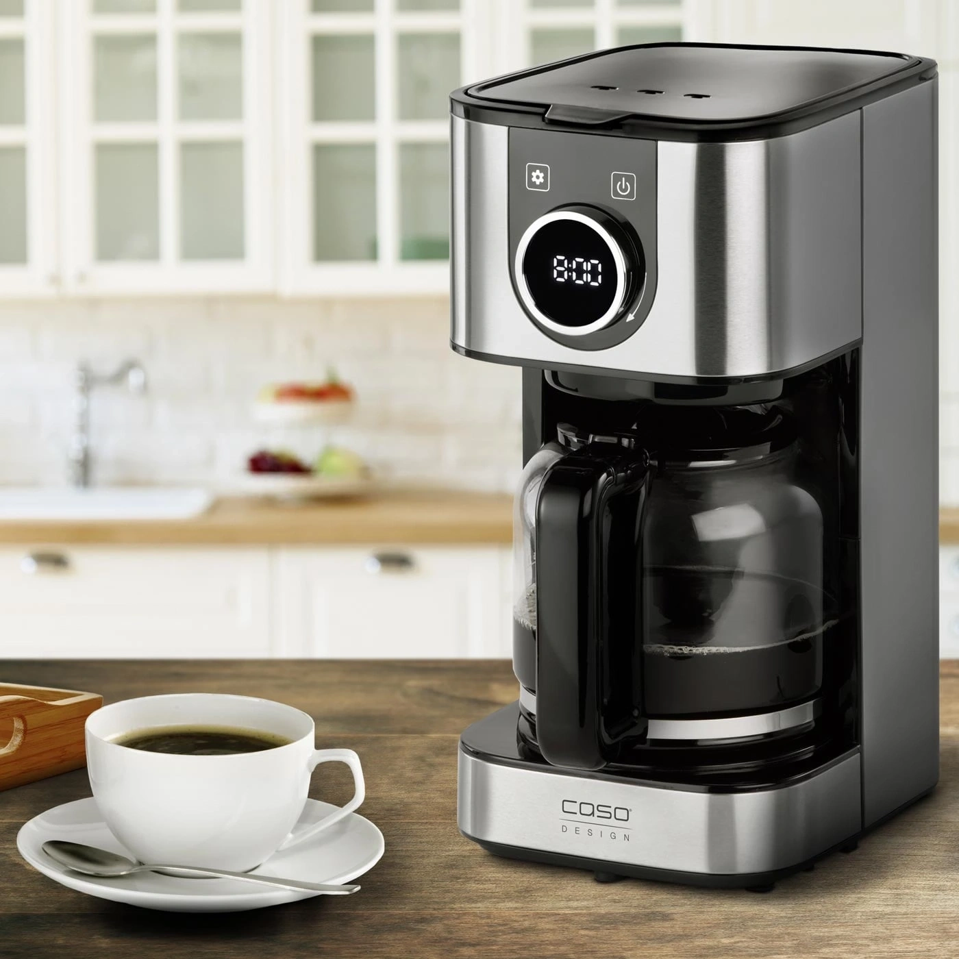 Coffee maker with a cup of coffee on a wooden table in the kitchen.