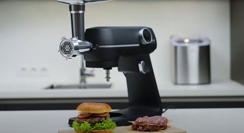 Meat grinder with burger and ground meat on a wooden board