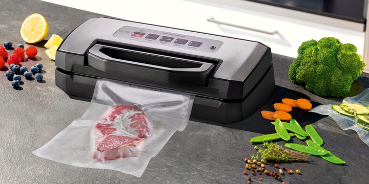 Vakuumiergerät mit Fleisch und Gemüse auf einer Arbeitsplatte