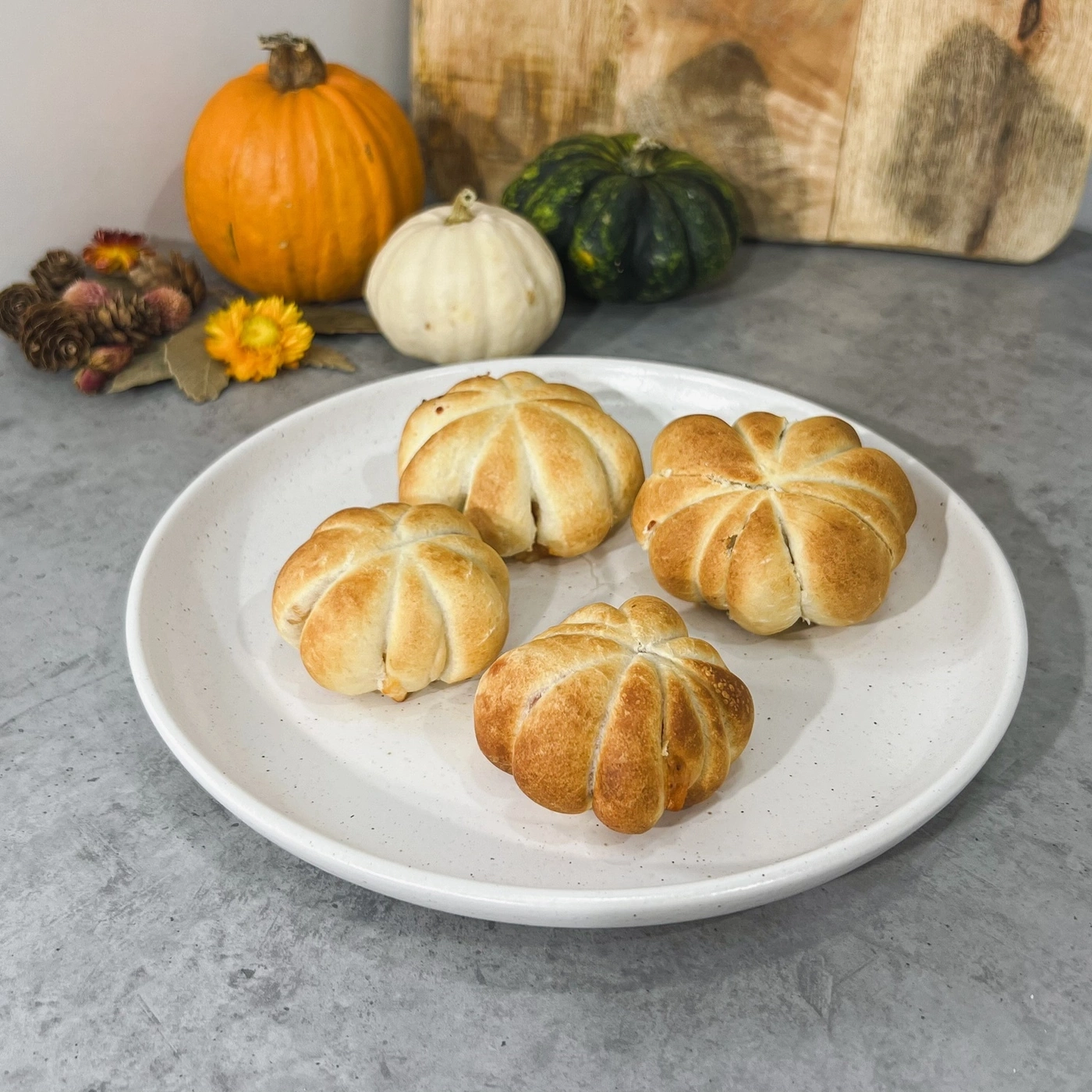 Teller mit Kürbisbrötchen, Kürbisse im Hintergrund, Herbstdekoration, Essen