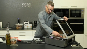 Man in kitchen with device, oil, knife, scale, Caso Design logo