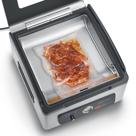 Vacuum sealer with meat in a bag, ready to seal and marinate for preservation.