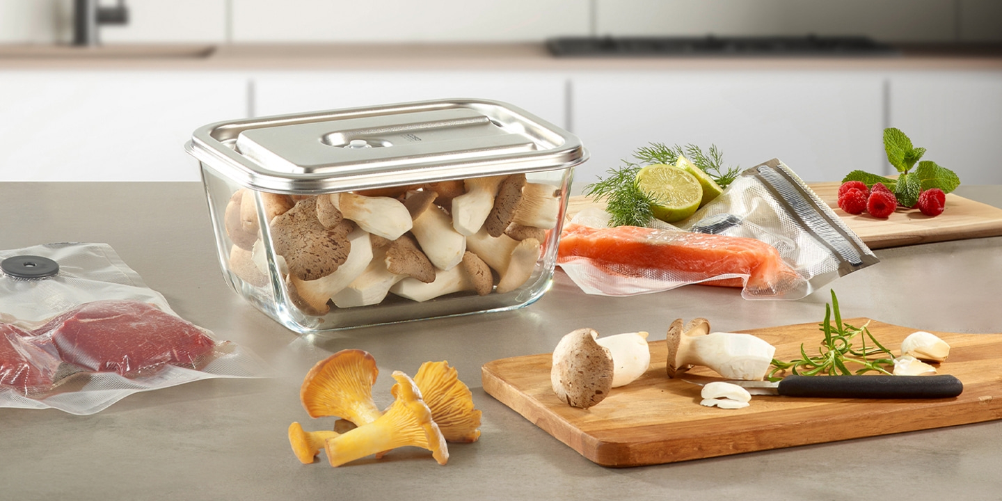 Frische Zutaten auf einer Küchenarbeitsplatte: Pilze, Fisch, Beeren, Kräuter.