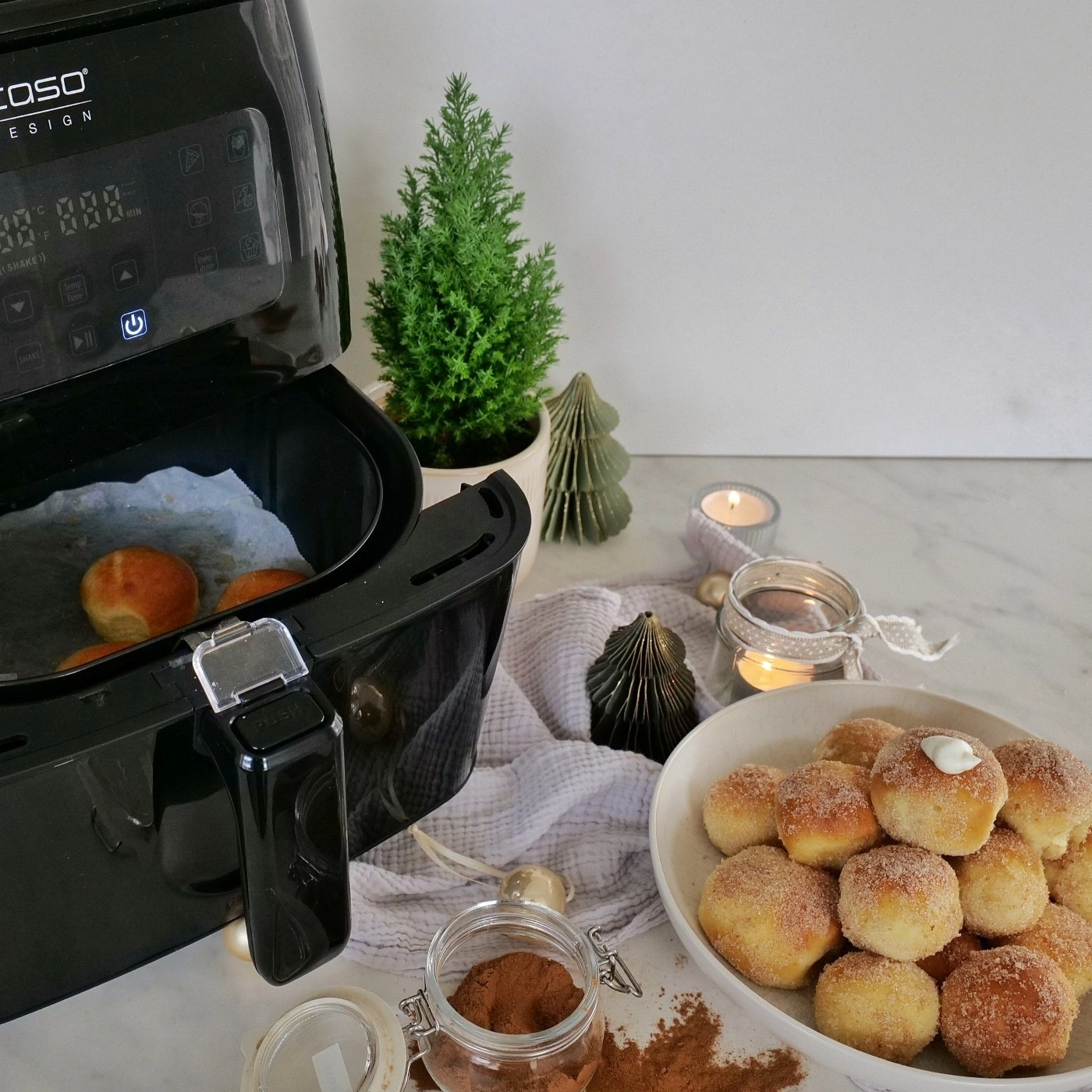 Air fryer with pastries, cinnamon, and decorations on a table