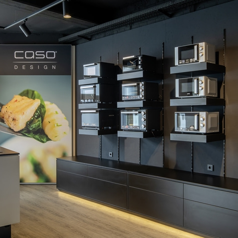 Display of microwaves in a modern store with dark walls and lighting, showcasing appliances.