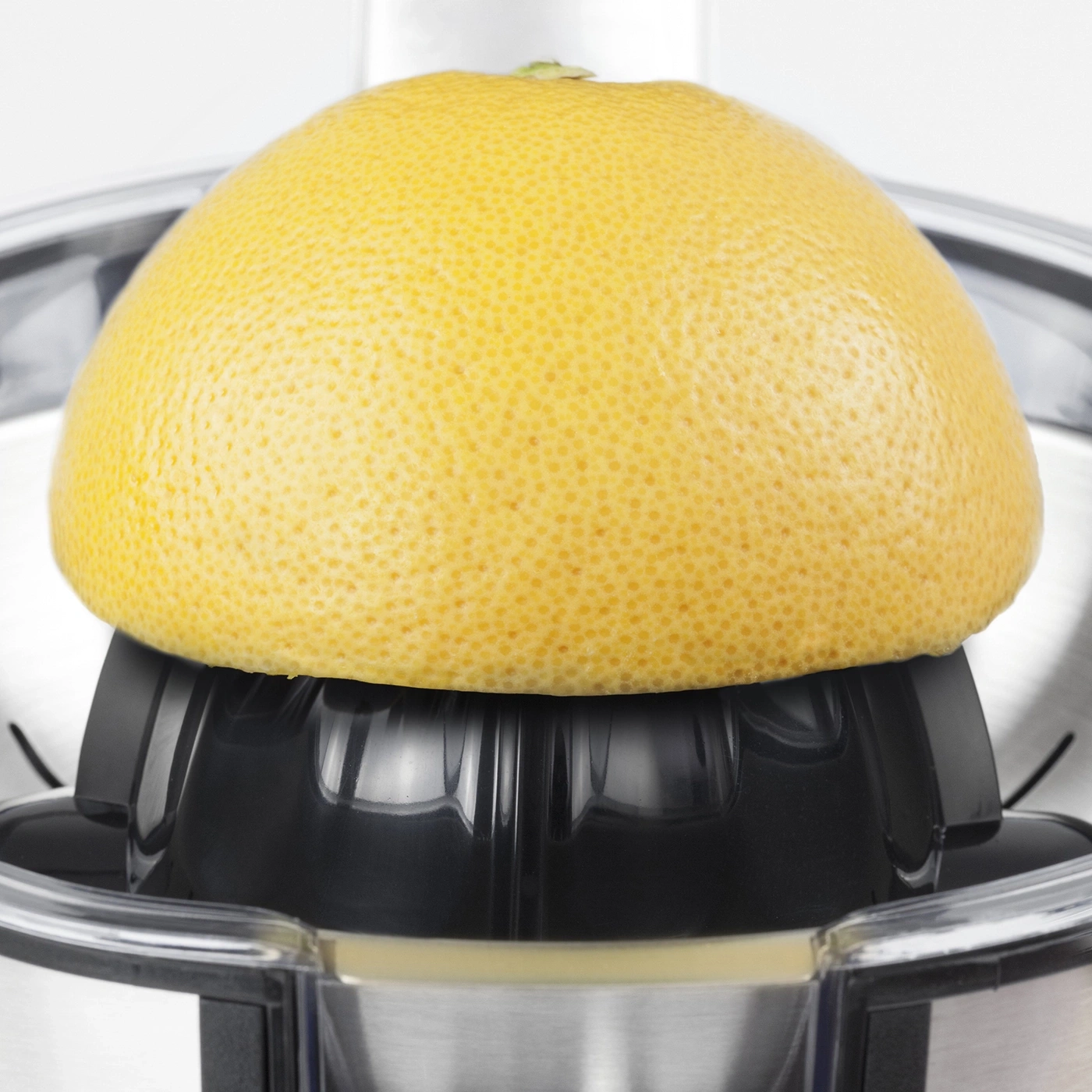 Grapefruit on a citrus juicer. Yellow fruit, black plastic, stainless steel.