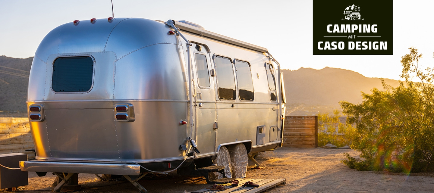 Silver camper in the desert at sunset, camping with Caso Design logo