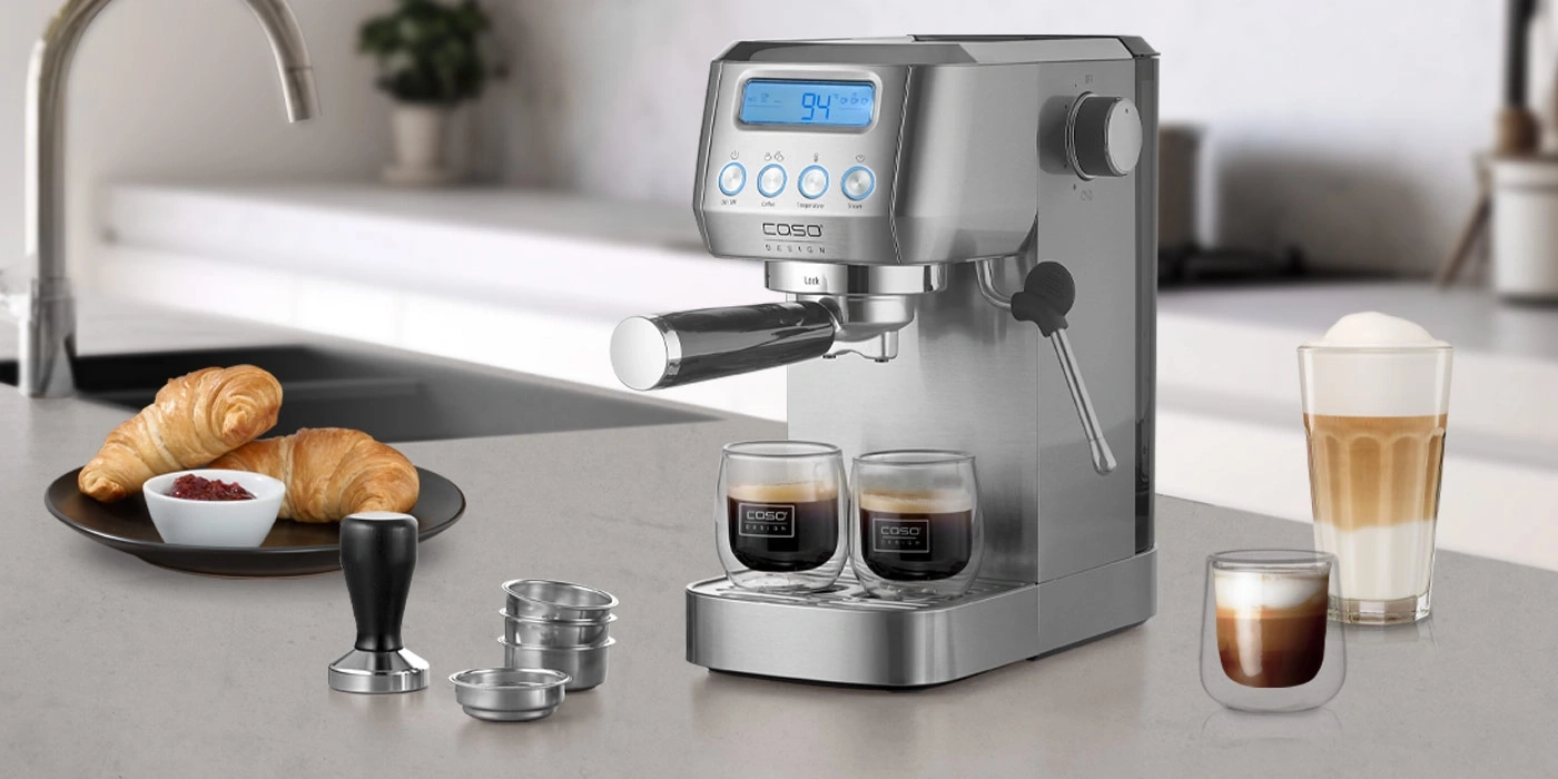 Kaffeemaschine mit Croissants und Kaffeegetränken auf einer Küchenarbeitsplatte.