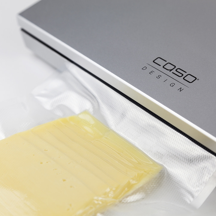 Cheese in plastic packaging next to a vacuum sealer with Caso Design logo.